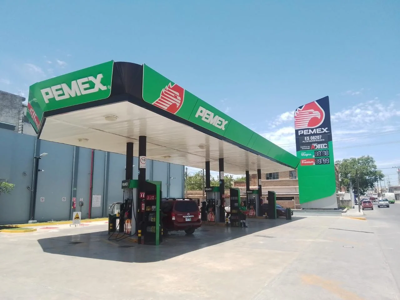 Canopy PEMEX y tótem junto a fachada gris